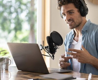 Junger Mann am Laptop spricht in ein Mikrophon