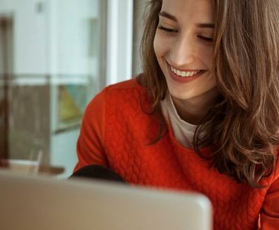 Frau sitzt lächelnd vor ihrem Laptop