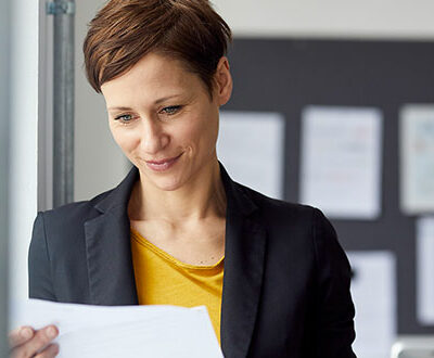 Eine Frau im Businessoutfit schaut auf ein Geschäftspapier in unserem Bewerbungscoaching