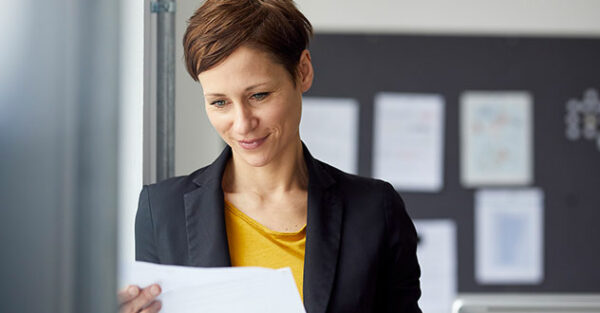 Eine Frau im Businessoutfit schaut auf ein Geschäftspapier in unserem Bewerbungscoaching
