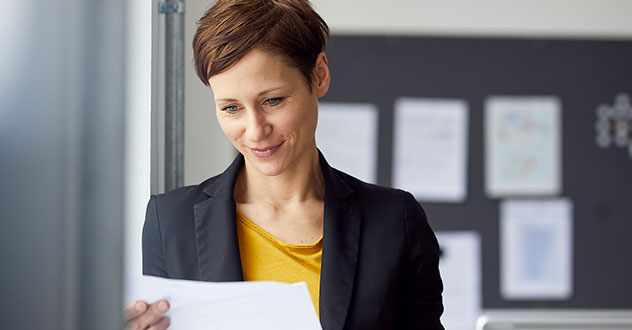 Eine Frau im Businessoutfit schaut auf ein Geschäftspapier in unserem Bewerbungscoaching