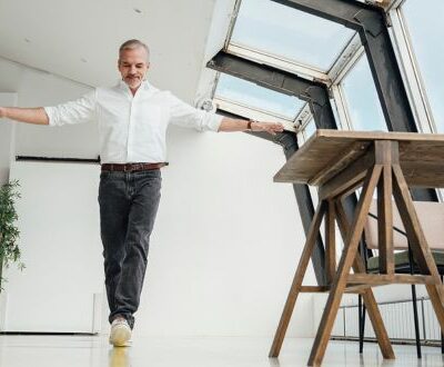 Ein Mann balanciert auf einer imaginären Linie mit ausgebreiteten Händen durch ein helles Arbeitszimmer