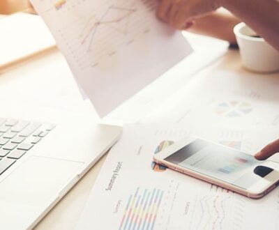 Schreibtisch mit Laptop, Taschenrechner und Kalkulationspapiere in unserem Businessplan Coaching