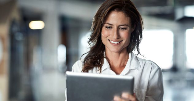 Frau schaut lächelt auf ein Laptop in unserem Digital Marketing Coaching