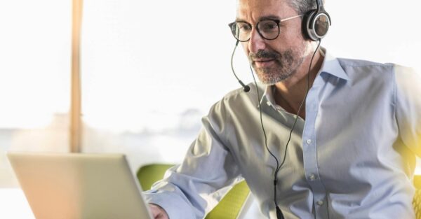 Ein Mann sitze mit Headset an einem Laptop in unserem Digitalisierungscoaching