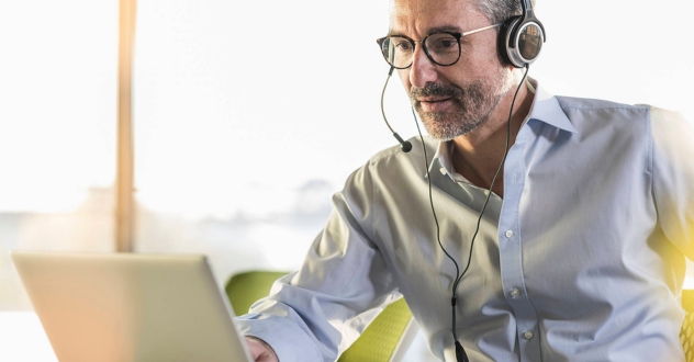 Ein Mann sitze mit Headset an einem Laptop in unserem Digitalisierungscoaching