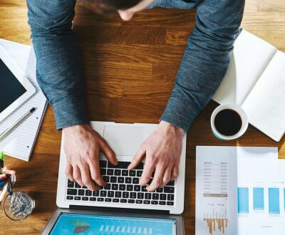 Ansicht von oben auf einen Mann der am Laptop tippt in unserem E-Commerce Coaching