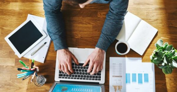Ansicht von oben auf einen Mann der am Laptop tippt in unserem E-Commerce Coaching
