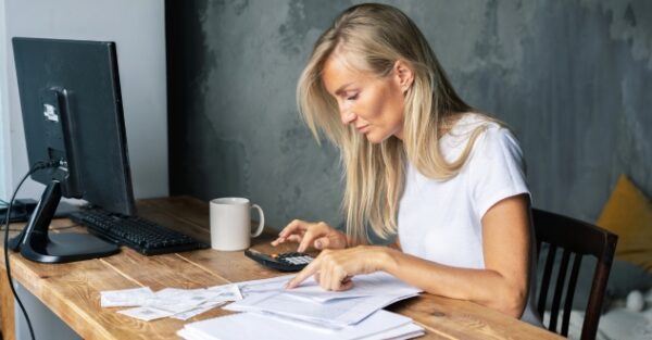 Frau itzt am Schreibtisch und kalkuliert mit einem Taschenrechner in unserem Finanzcoaching