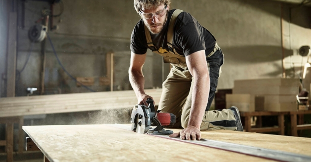 Ein Handwerker schneidet ein Brett mit einer Kreissäge in unserem Gründercoaching für Handwerker