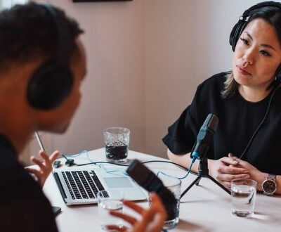 Interview Situation Mann und Frau mit Kopfhörern und Mirkrophon sitzen sich gegenüber