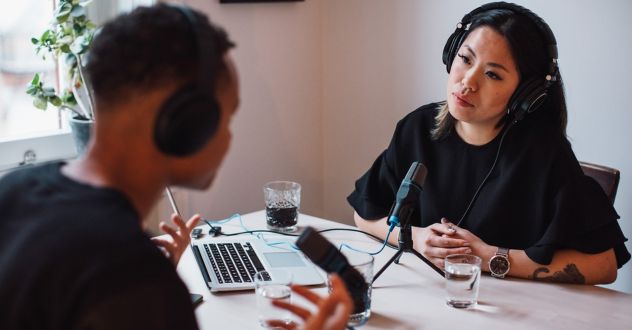 Interview Situation Mann und Frau mit Kopfhörern und Mirkrophon sitzen sich gegenüber
