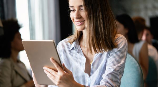 Eine junge Frau schaut aufmerksam auf ihr Tablet