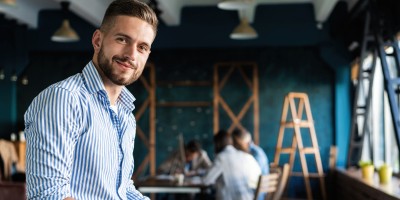 Junge Mann schaut zuversichtlich in die Kamera in unserem Gründercoaching