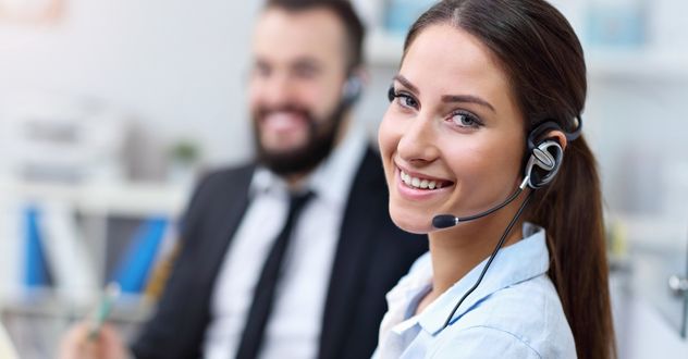 Frau schaut mit Headset lächelnd in die Kamera