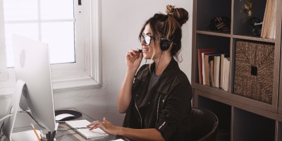 Junge Frau sitzt mit Headset vor einem Bildschirm in unserer E-Commerce Weiterbildung