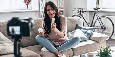 Junge Influencerin filmt sich und hält Kosmetikprodukte in die Kamera