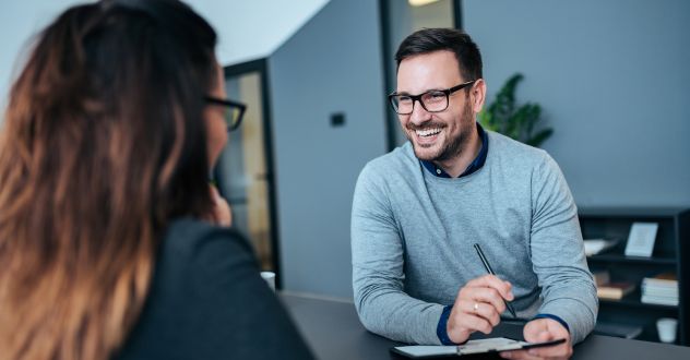 Coachingsituation: Ein Mann und eine Frau sitzen sich an einem Tisch gegenüber