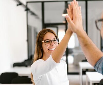 Ein Mann und eine Frauen klatschen sich im Büro ab