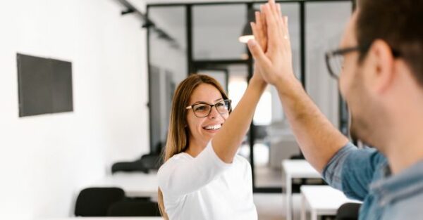 Ein Mann und eine Frauen klatschen sich im Büro ab