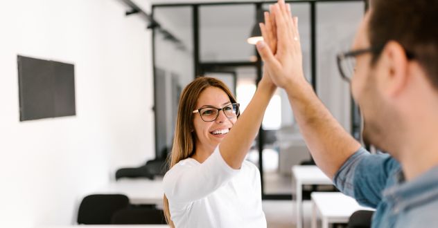 Ein Mann und eine Frauen klatschen sich im Büro ab