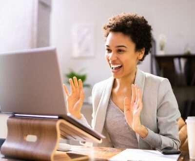 Junge Frau sitzt freudig am Laptop