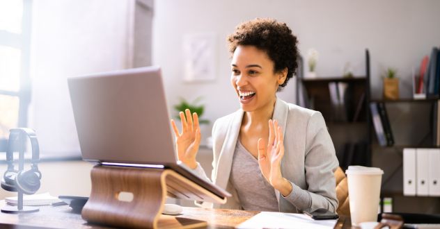 Junge Frau sitzt freudig am Laptop