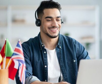 Junger Mann mit Headset sitzt am Laptop