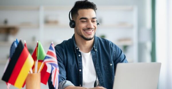 Junger Mann mit Headset sitzt am Laptop
