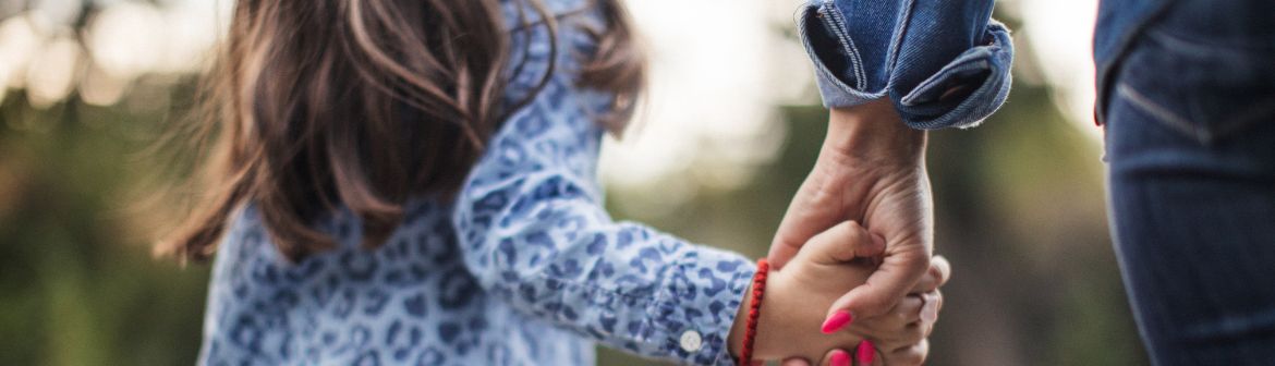 Eine Mutter hält die Hand ihres Kindes, während sie gemeinsam draußen unterwegs sind – Symbol für die Vereinbarkeit von Weiterbildung mit Kind und Familie