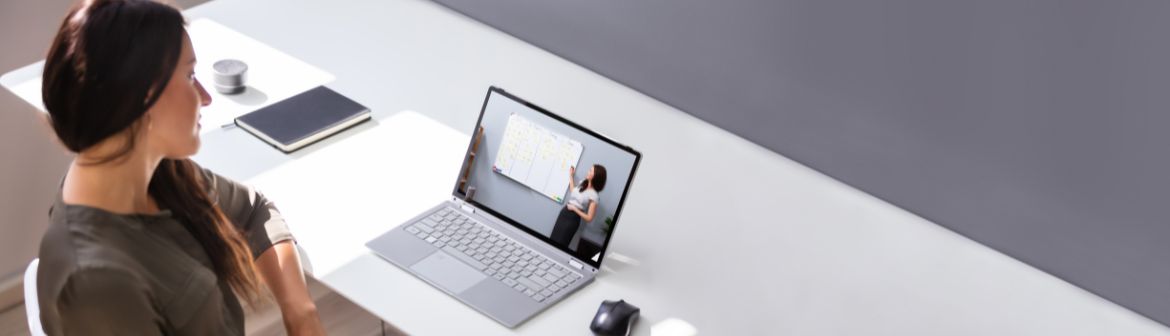 Frau nimmt an einem Online Coaching teil und verfolgt eine virtuelle Präsentation auf ihrem Laptop.