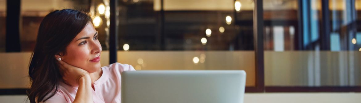 Nachdenkliche Frau vor einem Laptop in einem modernen Büro – Symbolbild für Quereinstieg im Online Marketing