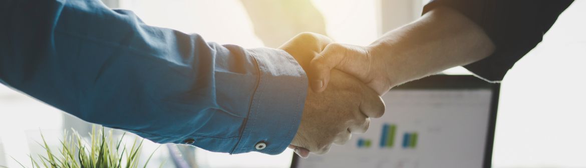 ein Geschäftsmann und eine Geschäftsfrau beim Handschlag, der im Anschnitt zu sehen ist, symbolisiert eine erfolgreiche Gehaltsverhandlung.